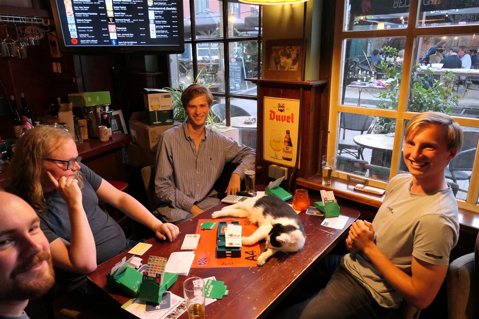 Groep jongeren bridgeclub met een kat op tafel