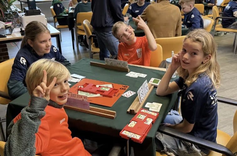 Kinderen spelen scholenbridge aan tafel met biedboxen
